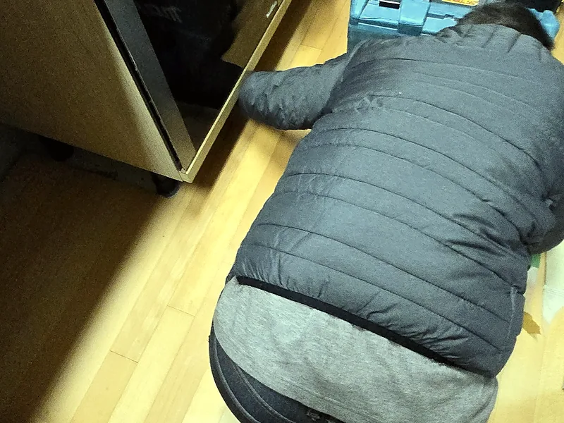 3단 서랍장 설치를 위해 하부 공간을 확인하는 기술자