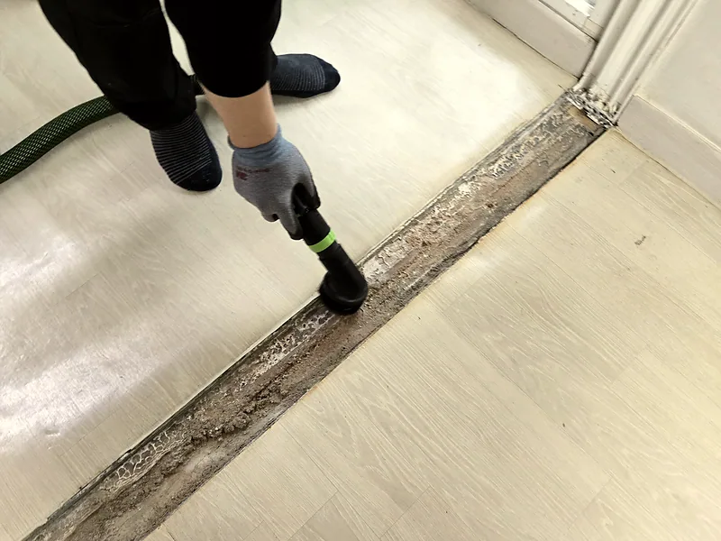거실 중문 문지방 제거 자리를 집진기로 청소하는 작업