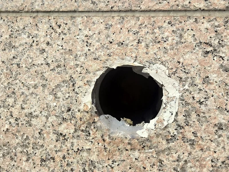 대리석 외벽 배관 구멍 복원 전 가장자리가 깨진 원형 타공
