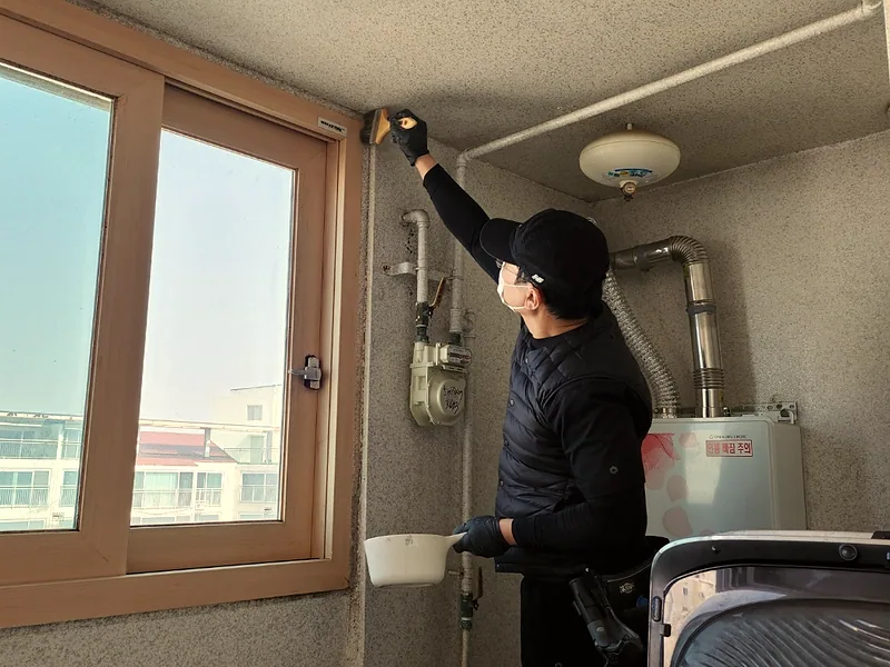 거주 아파트 곰팡이 청소 후 베란다 벽을 마무리 점검하는 작업자