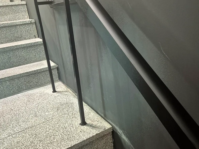 계단 난간대 설치 후 벽면을 따라 이어진 짙은 색 금속 손잡이