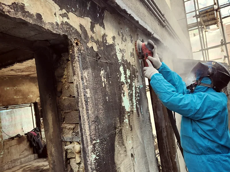 화재청소 중 샌더로 벽면 탄화층을 갈아내는 작업