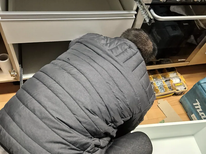 싱크대 서랍장 설치 중 하부장 내부 레일 위치를 확인하는 기술자