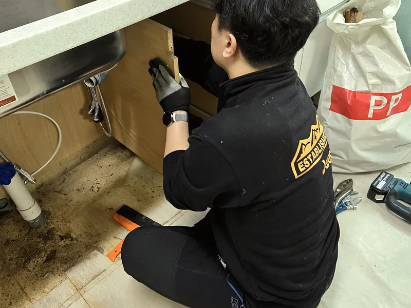 싱크대 부분수리 중 손상된 하부장을 철거하는 기술자