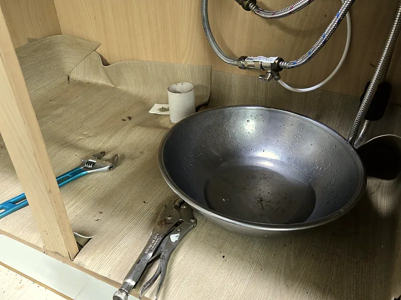싱크대 배수통 교체 중 하부장 안 받침 대야와 공구 배치